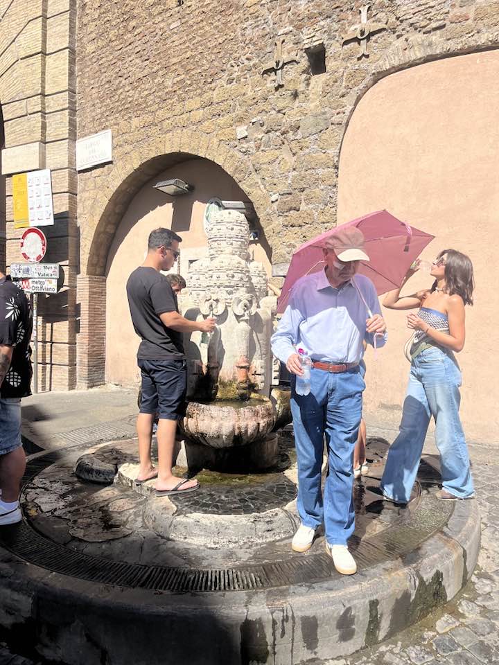 Fólk sækir sér vatn úr skrautlegum vatnsbrunni við Péturstorgið í Róm.